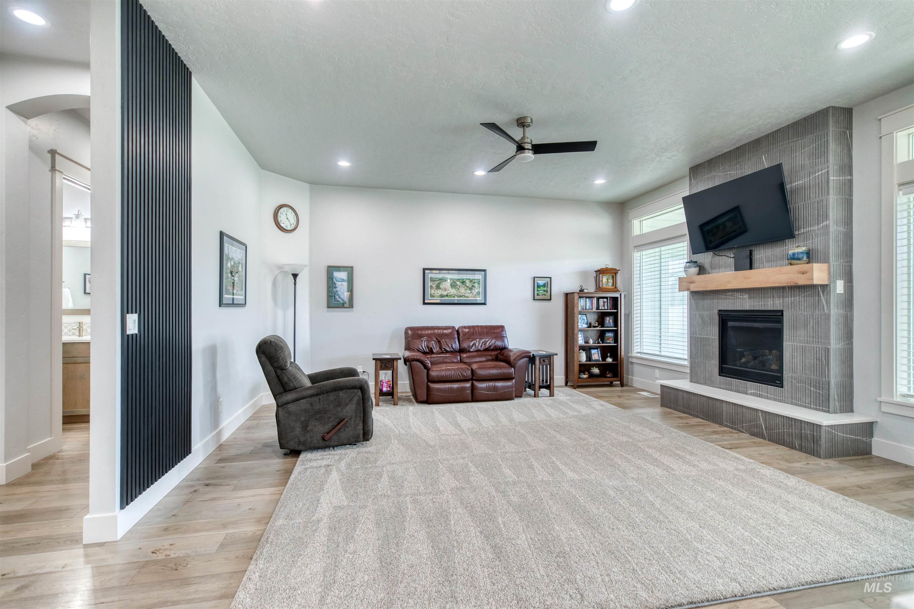 795 East Rio Chico Drive Kuna, ID 83634 - Photo 12 of 34 Living area featuring a tiled fireplace, recessed lighting, ceiling fan, light wood-style flooring, and arched walkways