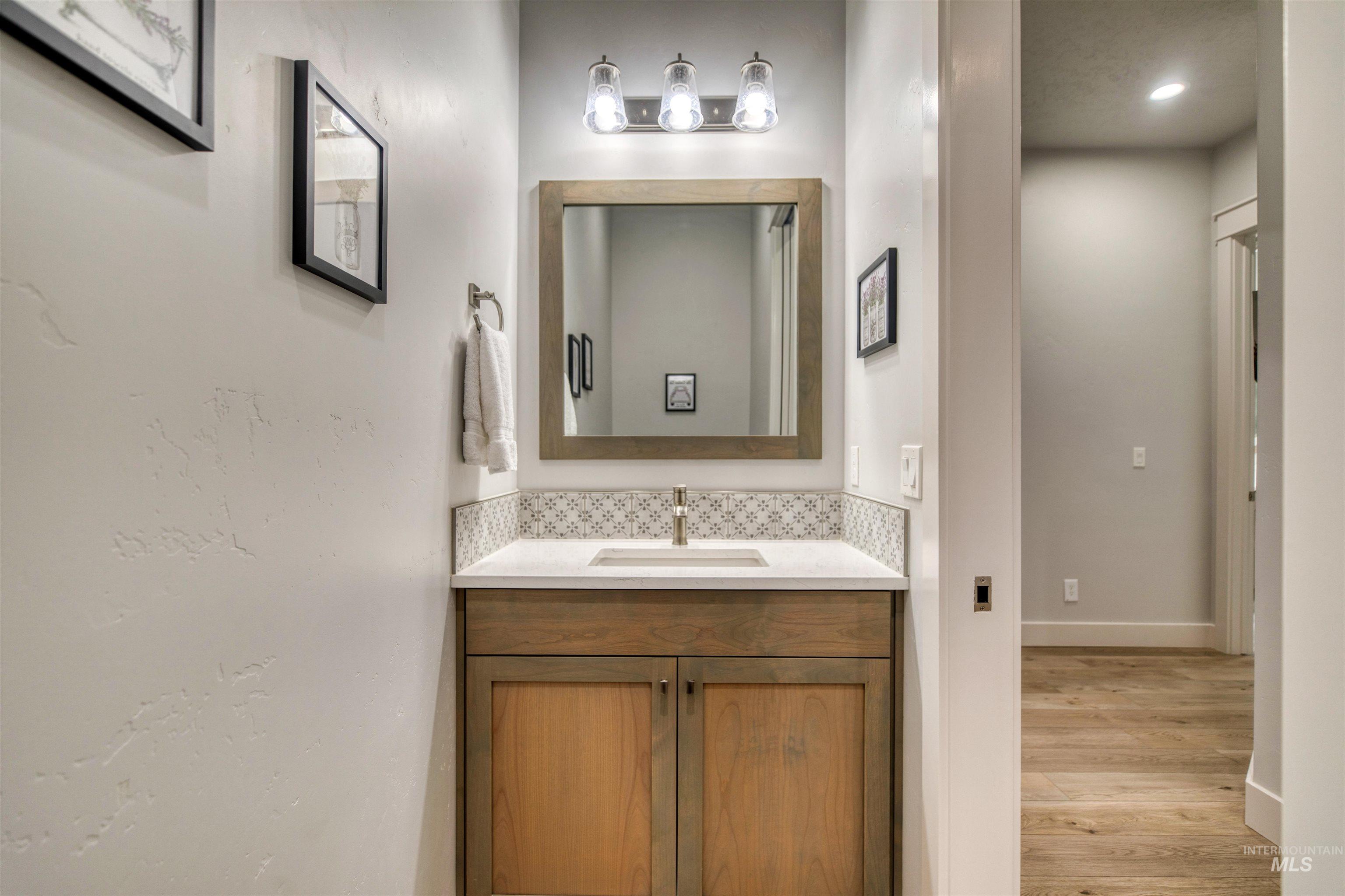 795 East Rio Chico Drive Kuna, ID 83634 - Photo 26 of 34 Half bathroom featuring vanity, light wood finished floors, and backsplash