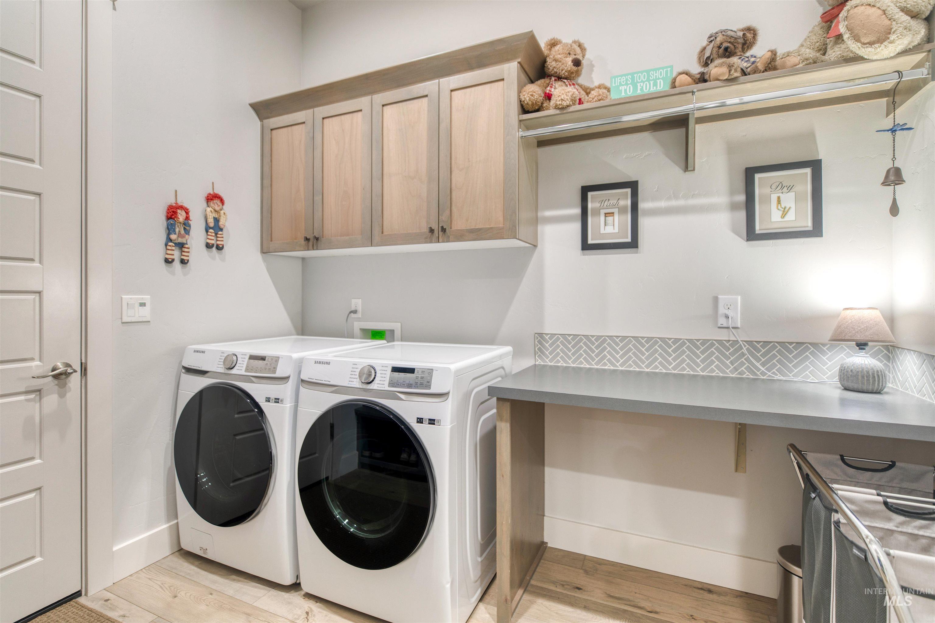 795 East Rio Chico Drive Kuna, ID 83634 - Photo 27 of 34 Laundry area featuring washing machine and dryer, light wood-type flooring, and cabinet space