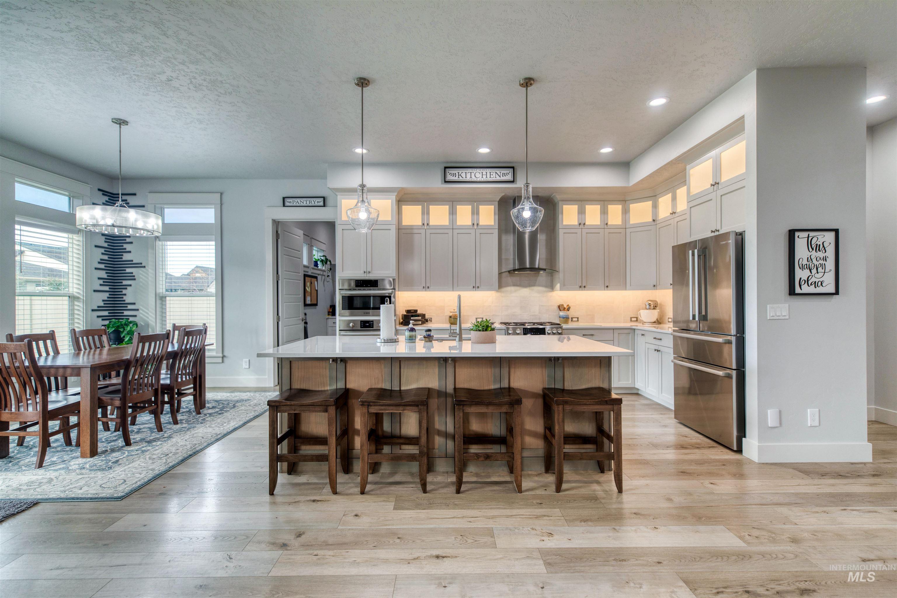 795 East Rio Chico Drive Kuna, ID 83634 - Photo 6 of 34 Kitchen with hanging light fixtures, an island with sink, a textured ceiling, stainless steel appliances, and a breakfast bar area