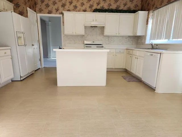 a kitchen with stainless steel appliances a stove a refrigerator a sink and white cabinets