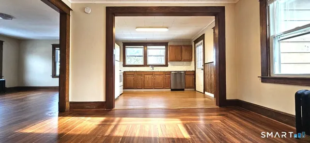a view of a hallway with wooden floor and a living room