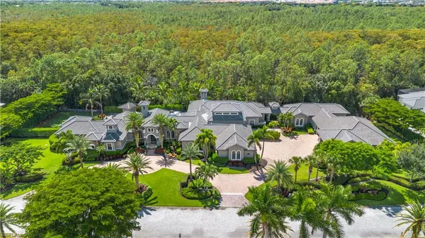an aerial view of residential house with outdoor space and trees all around