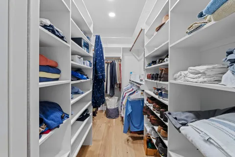 a view of walk in closet with clothes and shoes