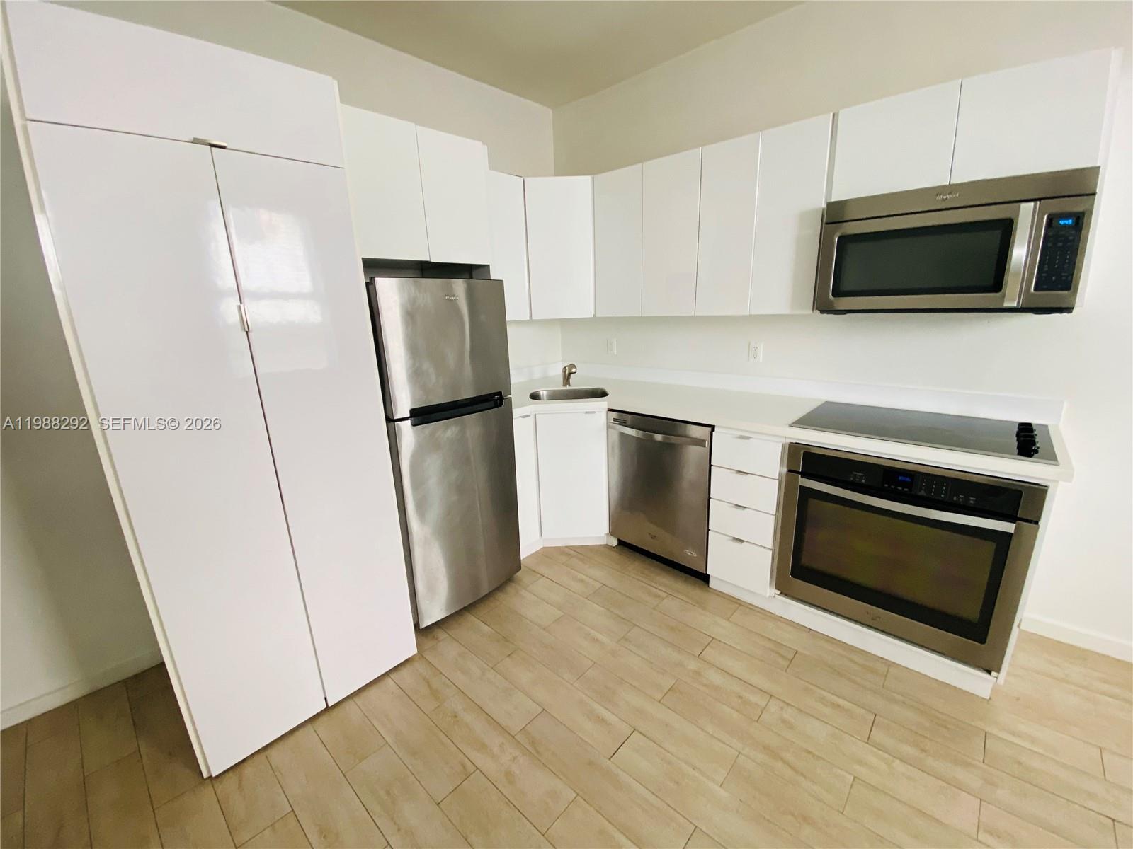 1611 Meridian Avenue, Unit 305 Miami Beach, FL 33139 - Photo 4 of 17 a kitchen with a refrigerator stove and wooden cabinets