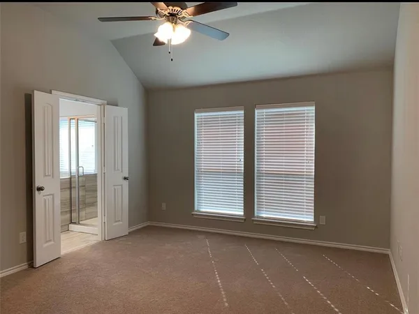 an empty room with windows and fan