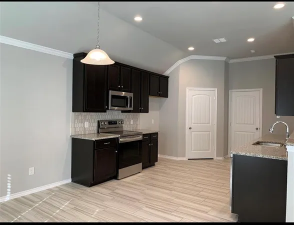 a open kitchen with kitchen island granite countertop a sink and a stove top oven with wooden floor