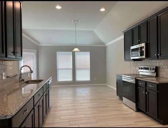 a kitchen with granite countertop a stove top oven sink and cabinets