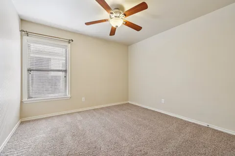 an empty room with a window and a fan