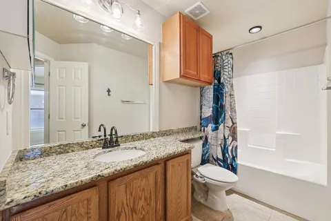 a bathroom with a granite countertop sink toilet and shower