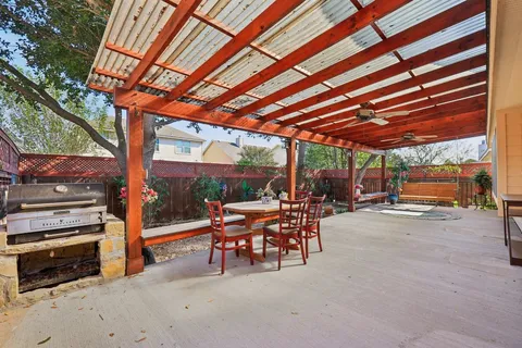 a patio with table and chairs and potted plants