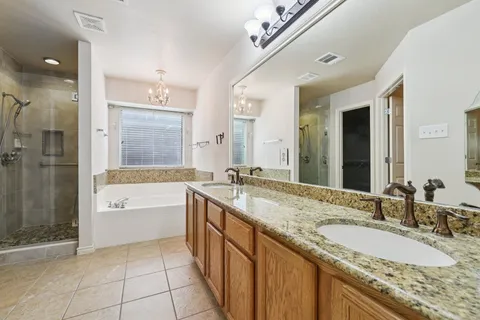 a bathroom with a granite countertop double vanity sink and a mirror