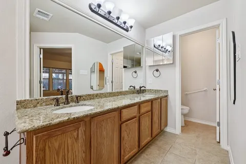a bathroom with a granite countertop double vanity sink and a mirror