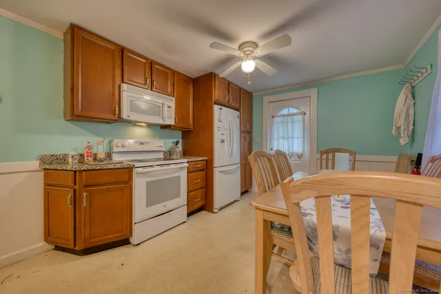 a kitchen with stainless steel appliances granite countertop a stove a sink dishwasher a refrigerator with a dining table and chairs with wooden floor