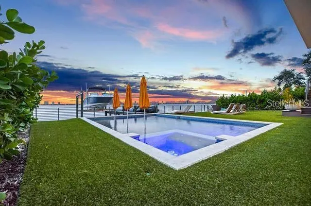 a view of a swimming pool with lawn chairs and a big yard