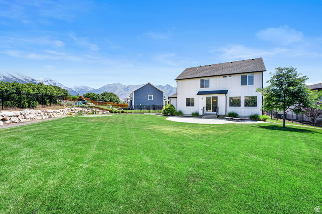 6536 West Muirfield Road Highland, UT 84003 - Photo 40 of 48 Expansive rear yard featuring a large manicured lawn, a concrete patio, and a retaining wall with rock landscaping