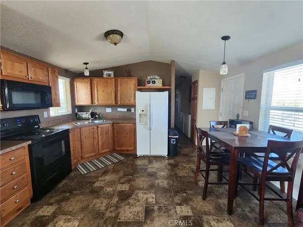 a kitchen with granite countertop a refrigerator a stove a sink dishwasher with a dining table and chairs