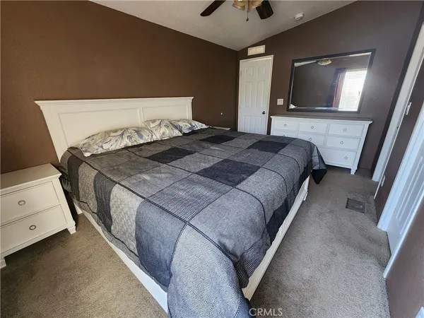 a bedroom with a bed and a flat tv screen on dresser