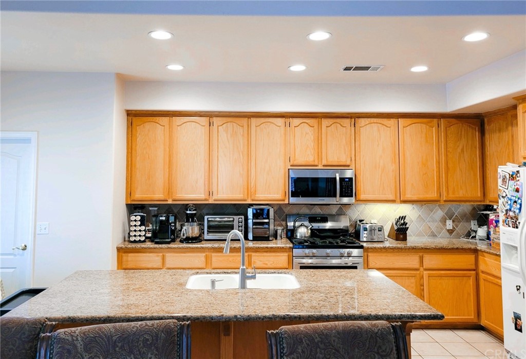 17157 Gamble Avenue Riverside, CA 92504 - Photo 4 of 11 a kitchen with stainless steel appliances granite countertop a stove top oven a sink a counter space and cabinets