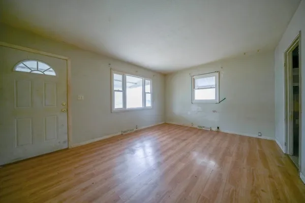 a view of an empty room with wooden floor and a window