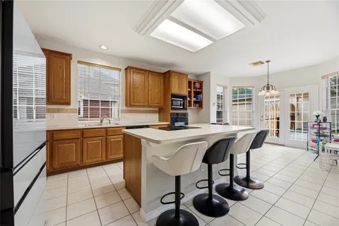 a kitchen with stainless steel appliances granite countertop a sink a stove and chairs with wooden floor