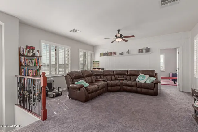 a living room with furniture a ceiling fan and a book shelf