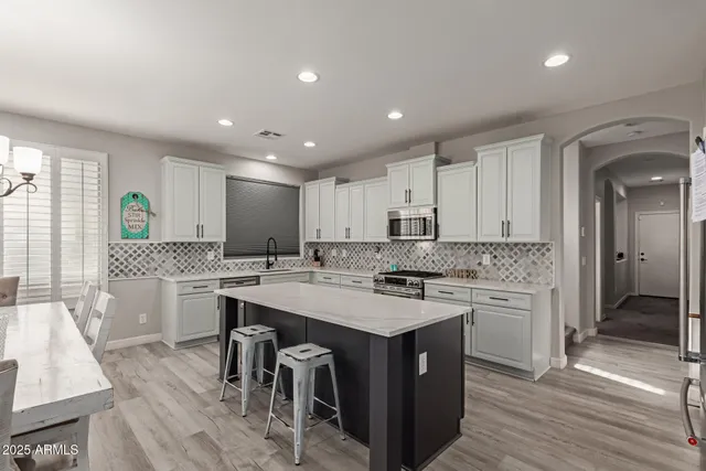 a kitchen with a stove a sink a refrigerator and chairs