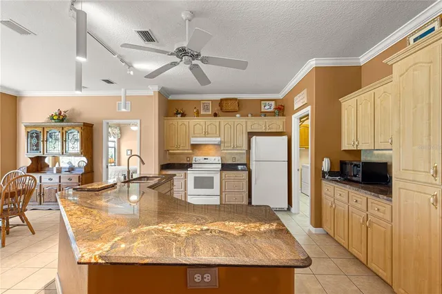 a view of a kitchen with kitchen island granite countertop a refrigerator stove microwave and cabinets