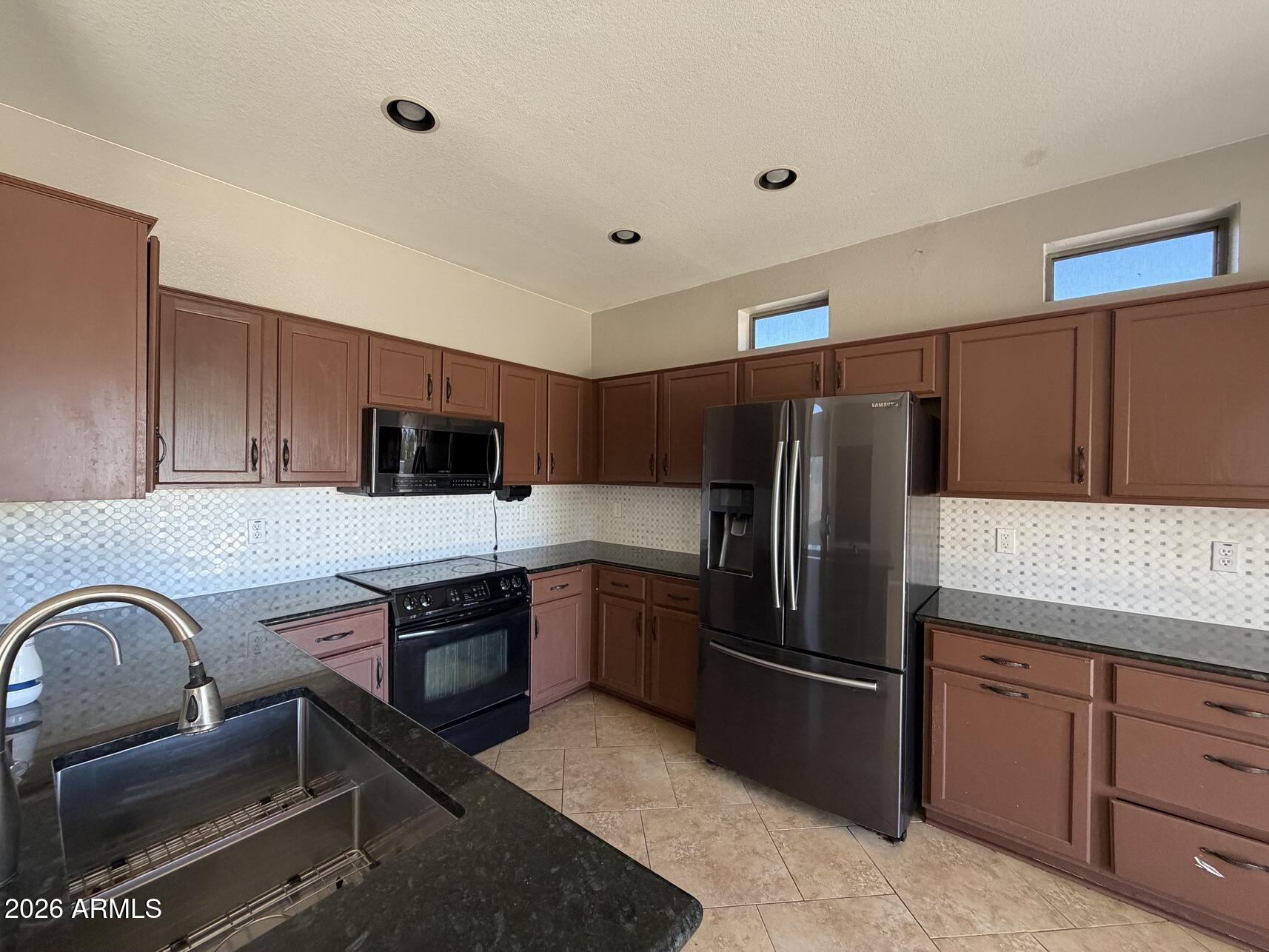 10807 West Monte Vista Road Avondale, AZ 85392 - Photo 11 of 33 a kitchen with stainless steel appliances granite countertop a refrigerator and a stove top oven