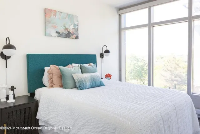a large white bed in a bedroom next to a window