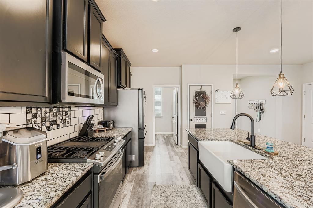 429 Rusk Bluff Avenue Leander, TX 78641 - Photo 5 of 24 An inviting kitchen showcasing a generous island with a farmhouse sink and modern pendant lighting.