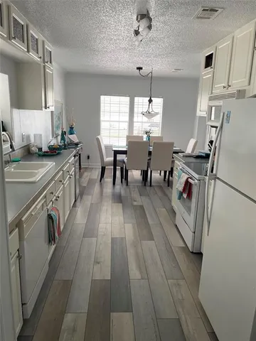 a kitchen with stainless steel appliances granite countertop a stove top oven a sink dishwasher and white cabinets with wooden floor