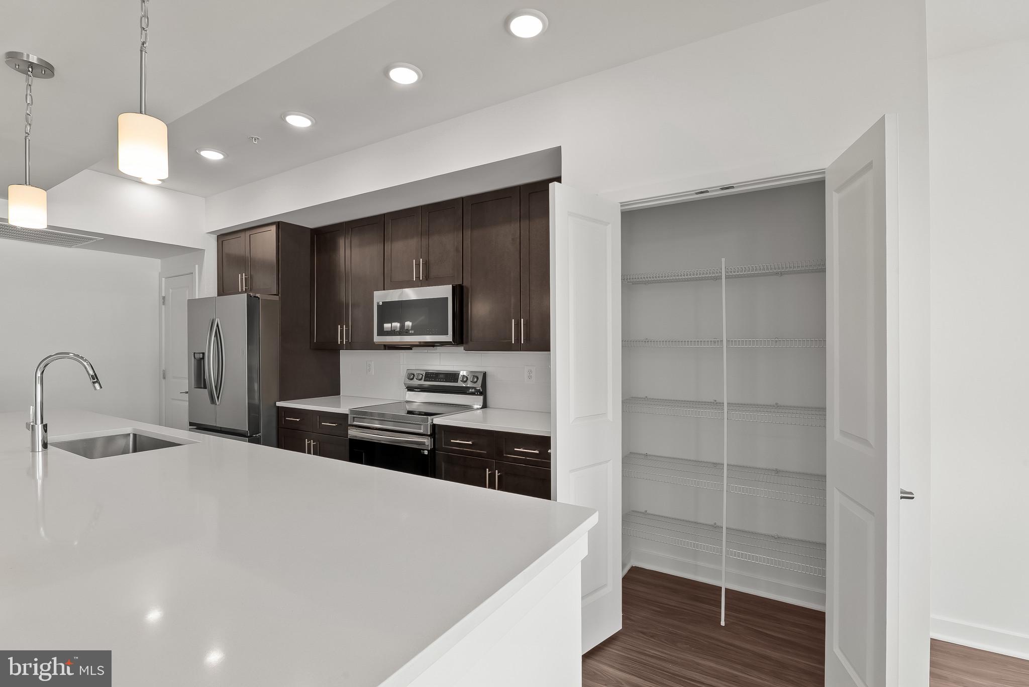 714 D Iron Frg Road Frederick, MD 21702 - Photo 11 of 47 a kitchen with a refrigerator a stove and a sink with wooden floor