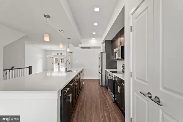 a kitchen with kitchen island a counter top space a sink a stove and wooden floor