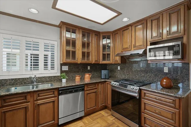 a kitchen with granite countertop cabinets stainless steel appliances and a sink