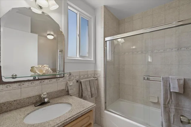 a bathroom with a granite countertop sink a mirror and a bathtub