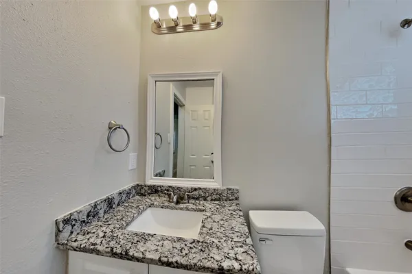 a bathroom with a granite countertop sink a toilet and mirror