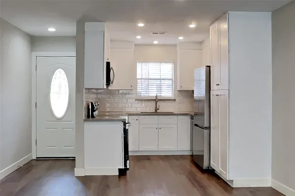 a kitchen with stainless steel appliances granite countertop a sink a stove a refrigerator and island with wooden floor