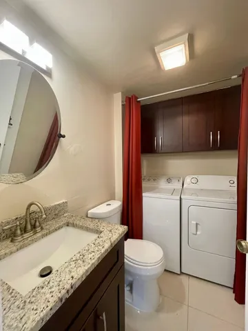 a bathroom with a granite countertop toilet sink and mirror