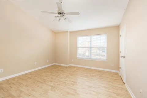 an empty room with a chandelier fan and windows