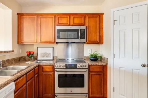 a kitchen with stainless steel appliances granite countertop a stove a sink and a microwave