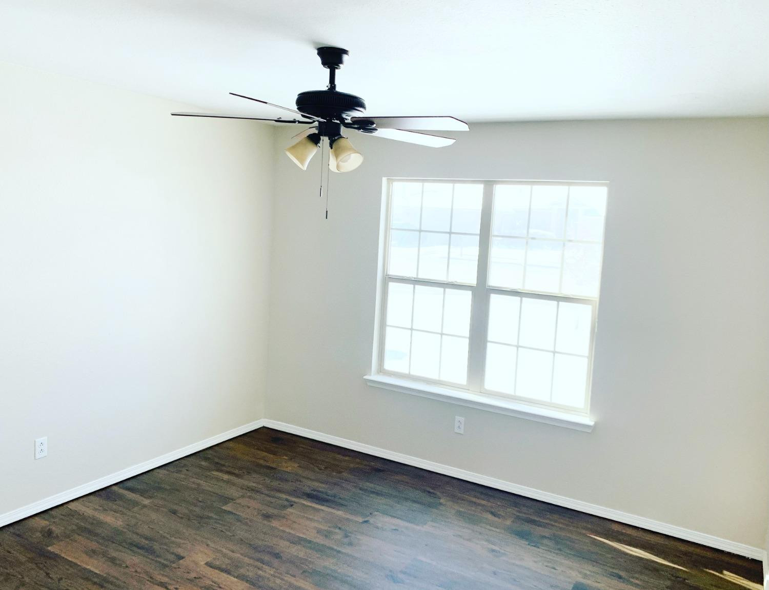 9807 Juneau Avenue Lubbock, TX 79424 - Photo 18 of 22 an empty room with wooden floor fan and windows