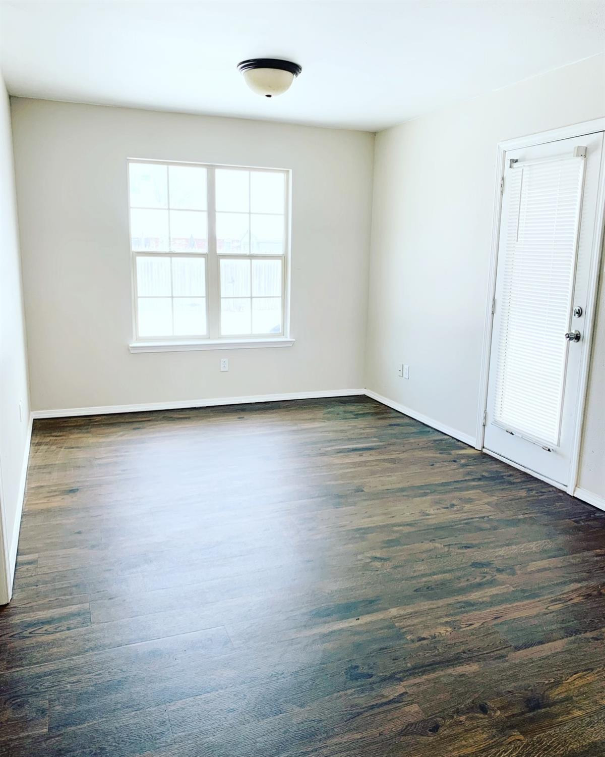 9807 Juneau Avenue Lubbock, TX 79424 - Photo 10 of 22 an empty room with wooden floor and windows