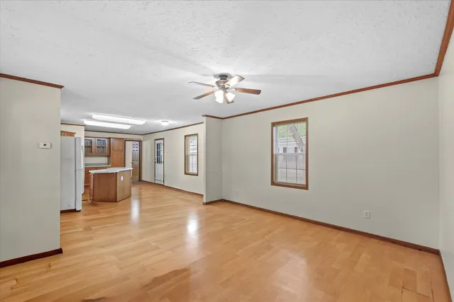 a view of an empty room with a window and kitchen view