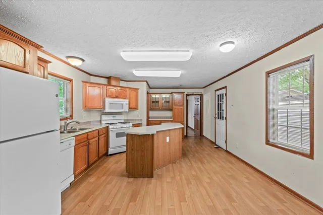 a kitchen with stainless steel appliances granite countertop a stove a refrigerator a sink dishwasher and a dining table with wooden floor