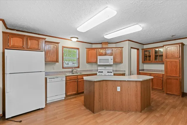 a kitchen with stainless steel appliances granite countertop a stove a refrigerator a sink and dishwasher with wooden floor