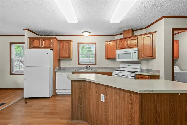 a kitchen with a refrigerator a stove a sink dishwasher and wooden cabinets with wooden floor