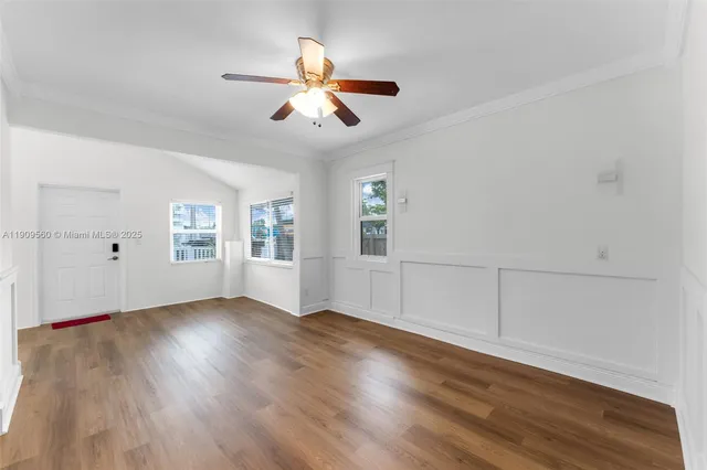 an empty room with wooden floor chandelier fan and windows