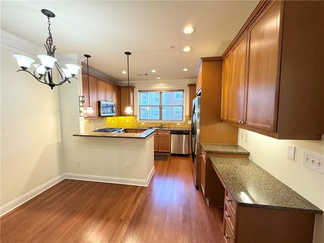 a kitchen with stainless steel appliances granite countertop wooden floors sink and cabinets