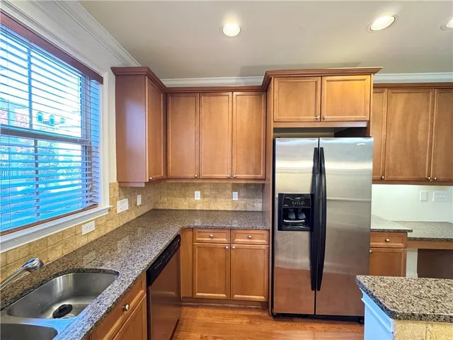 a kitchen with granite countertop a sink a refrigerator and wooden cabinets